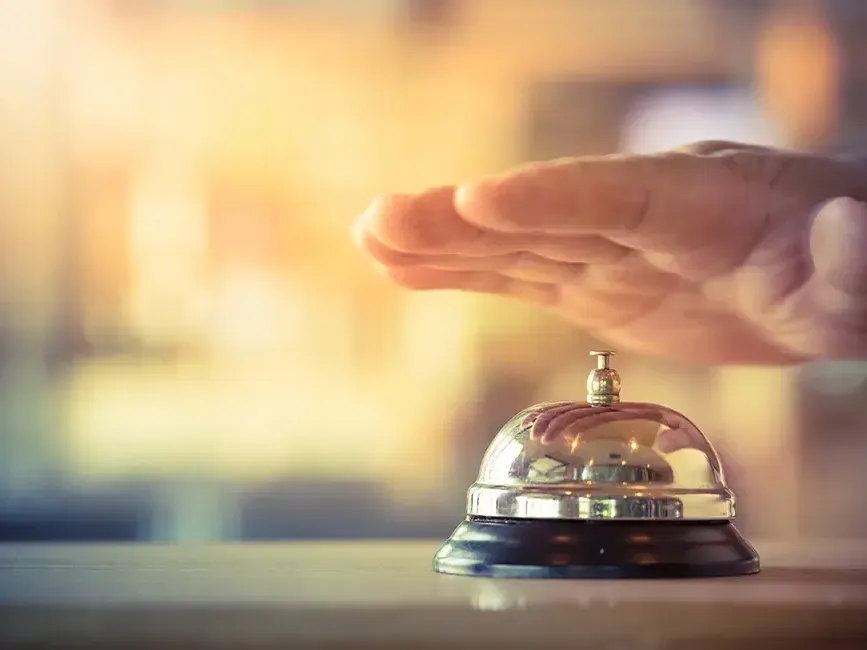 A hand reaching out to press the hotel bell on a reception desk - Imperial Lexis Kuala Lumpur