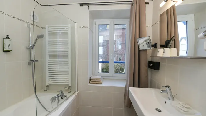 Salle de bain élégante avec baignoire, lavabo et fenêtre à l'Hôtel Villa Aultia.