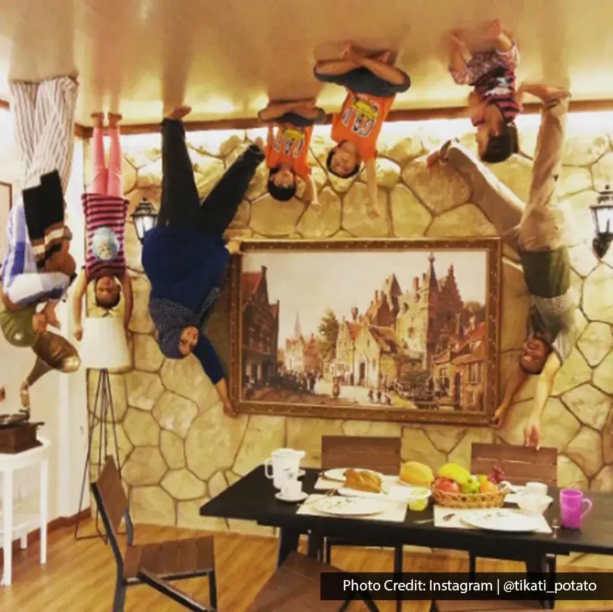 Family enjoying upside down dining illusion with table and chairs at Upside Down Museum.
