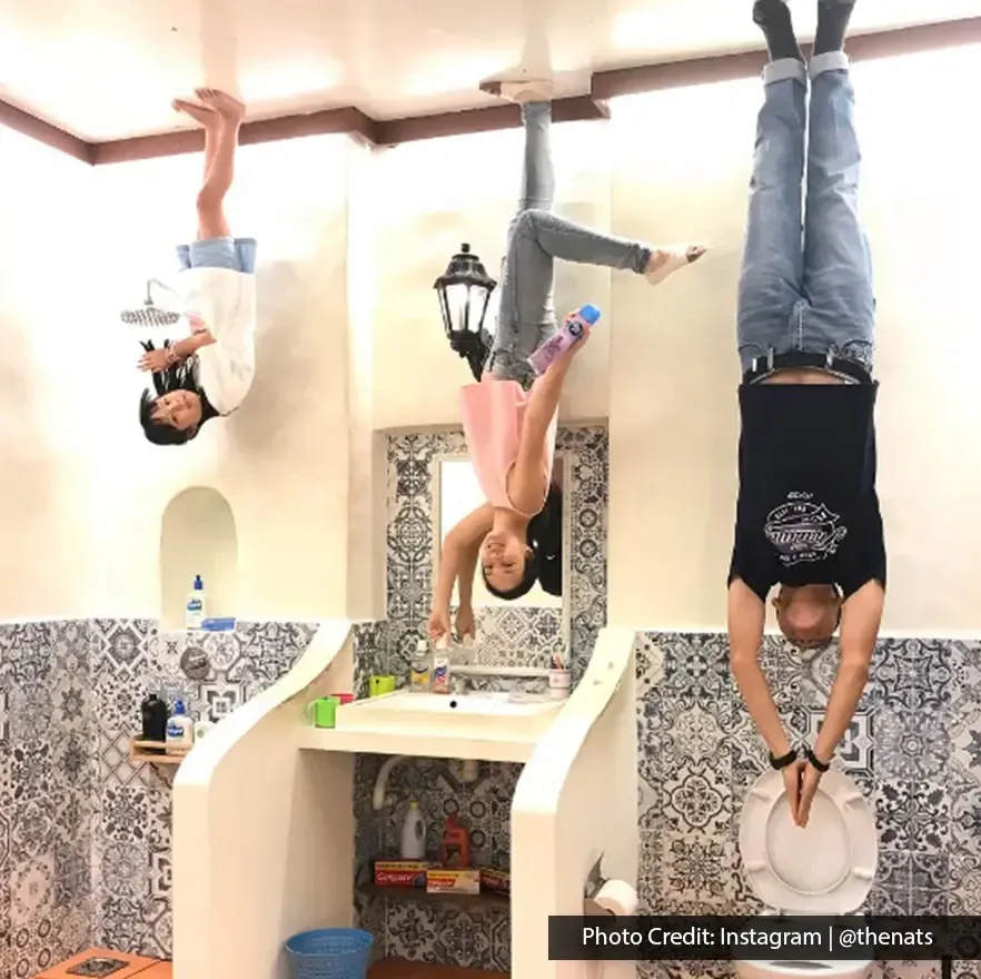 Family posing upside down in a bathroom setup at Upside Down Museum.
