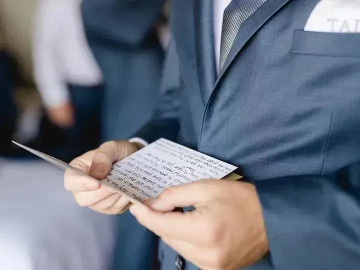 Man in blue suit holding a handwritten note, focused and thoughtful at Fiesta Americana Travelty