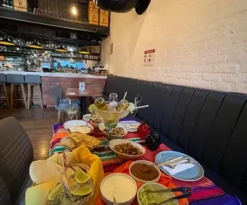 Long dark leather banquet sofa along set dining tables arranged with vibrant Mexican dishes at Unika Hotels