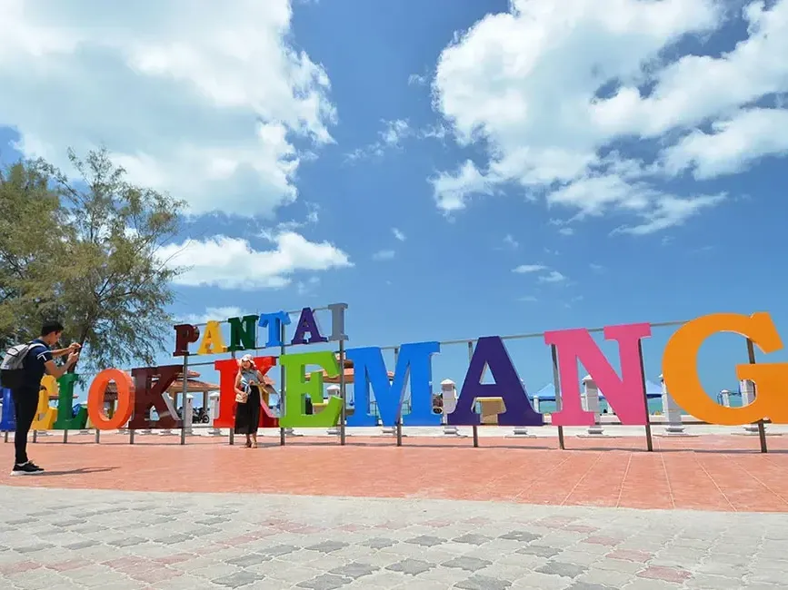 A man taking a photo of the colourful Teluk Kemang Beach signage - Lexis Port Dickson