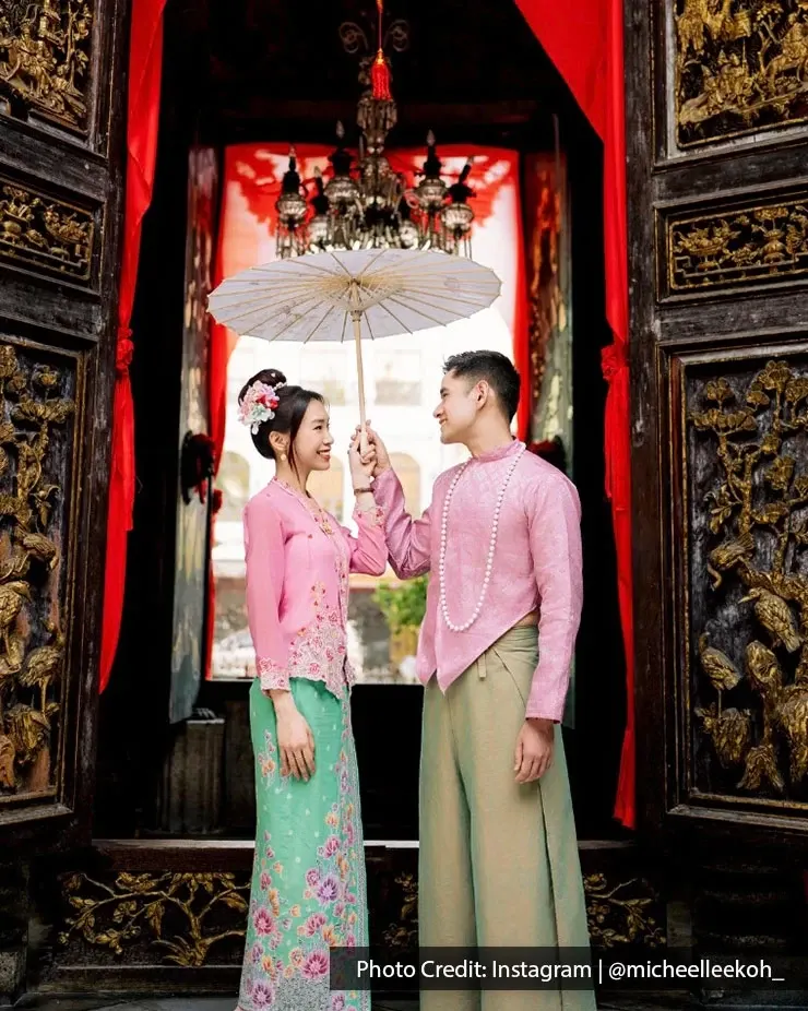 Man and woman wearing Nyonya kebaya and batik posing at Pinang Peranakan Mansion in Penang.