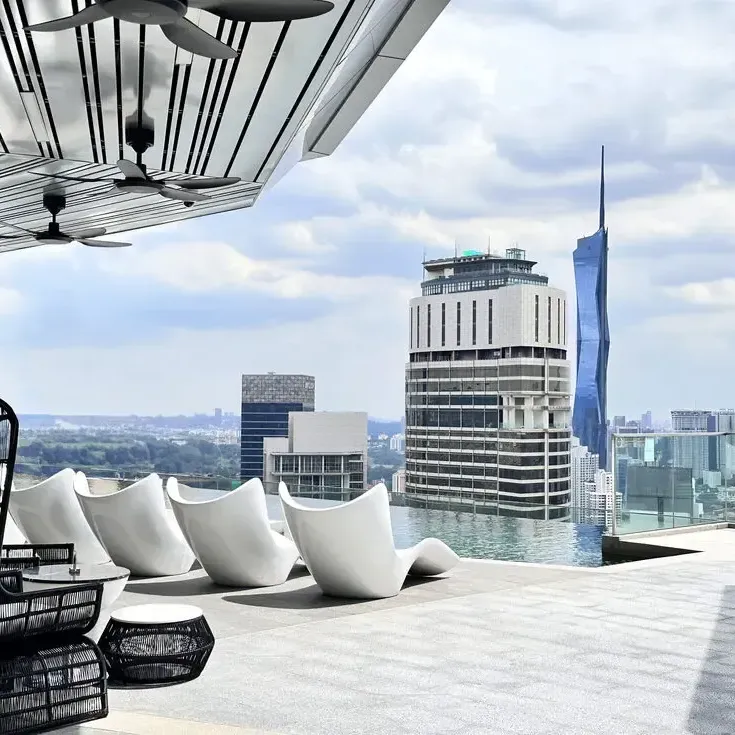 Rooftop pool with lounge chairs overlooking a vibrant city skyline at Imperial Lexis Kuala Lumpur - Lexis Hotels & Resorts