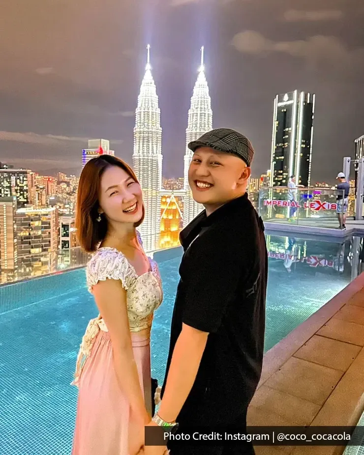 A couple poses by a private pool with the Petronas Towers in the background at night.