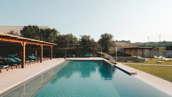 Piscine extérieure entourée de chaises longues et de verdure à Masseria Stali, Caprarica di Lecce.