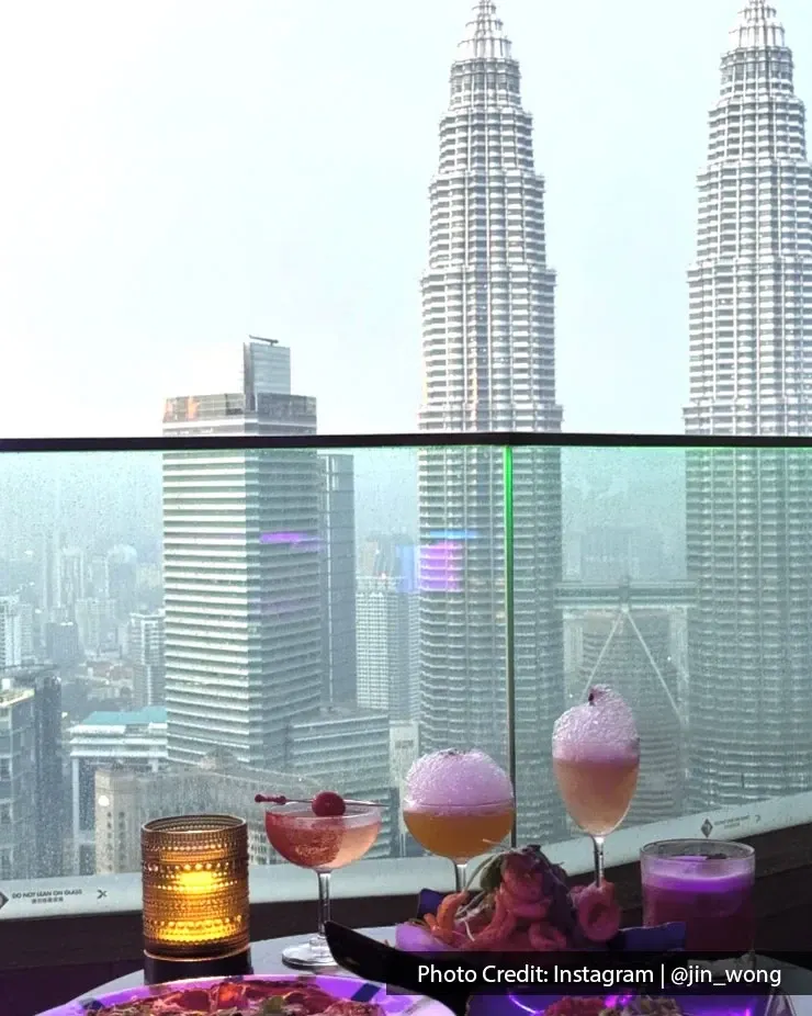 A birthday dinner scene at a restaurant with a panoramic view of Kuala Lumpur's skyline.