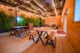Mesas de picnic de madera en patio de espiga con luces colgantes bajo un techo de cristal en Hotel B3 Virrey
