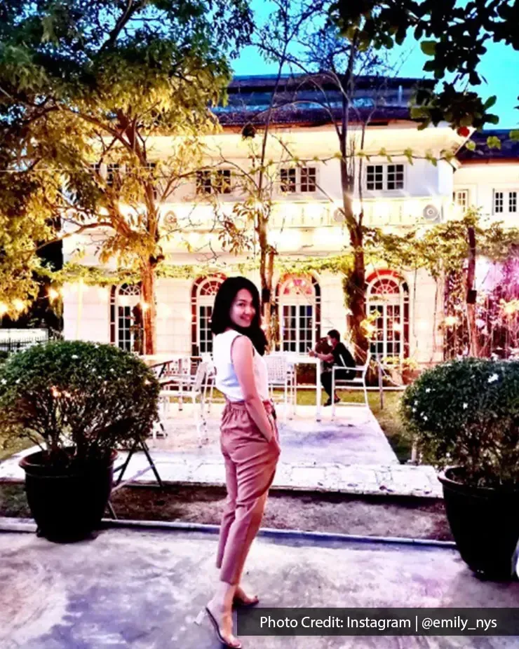 Woman posing in front of Beach Blanket Babylon.