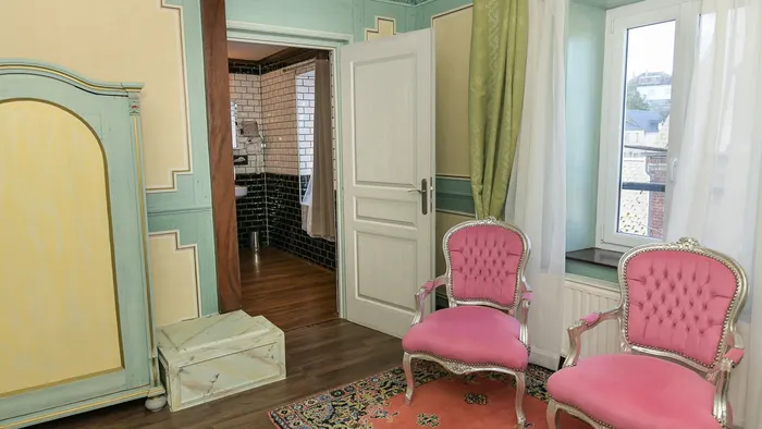 Deux chaises roses et élégantes dans une chambre décorée avec goût à l'Hôtel Villa Aultia.