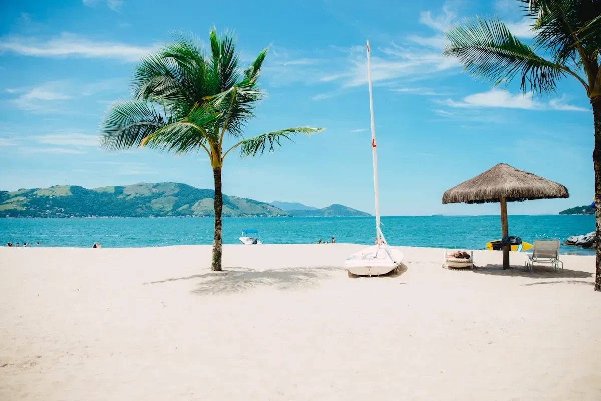 Palm trees and a small sailboat on a bright sandy beach