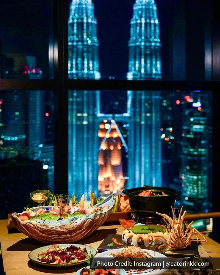 A dining table adorned with dishes, featuring a view of the iconic Petronas Towers in the background.