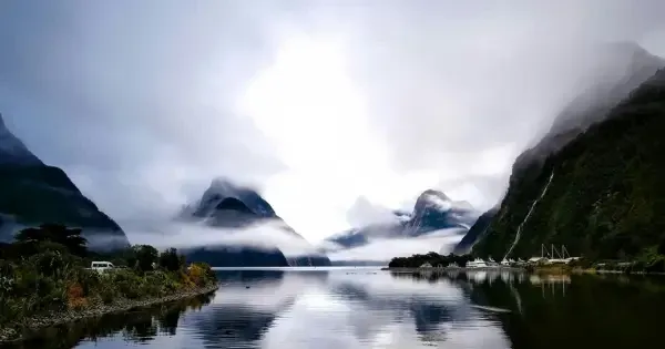 Small boats float on glass-like waters in Milford Sound on a famously cloudy day