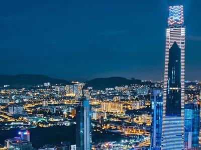 A nighttime cityscape with multiple illuminated skyscrapers and a prominent tall building with blue lights.