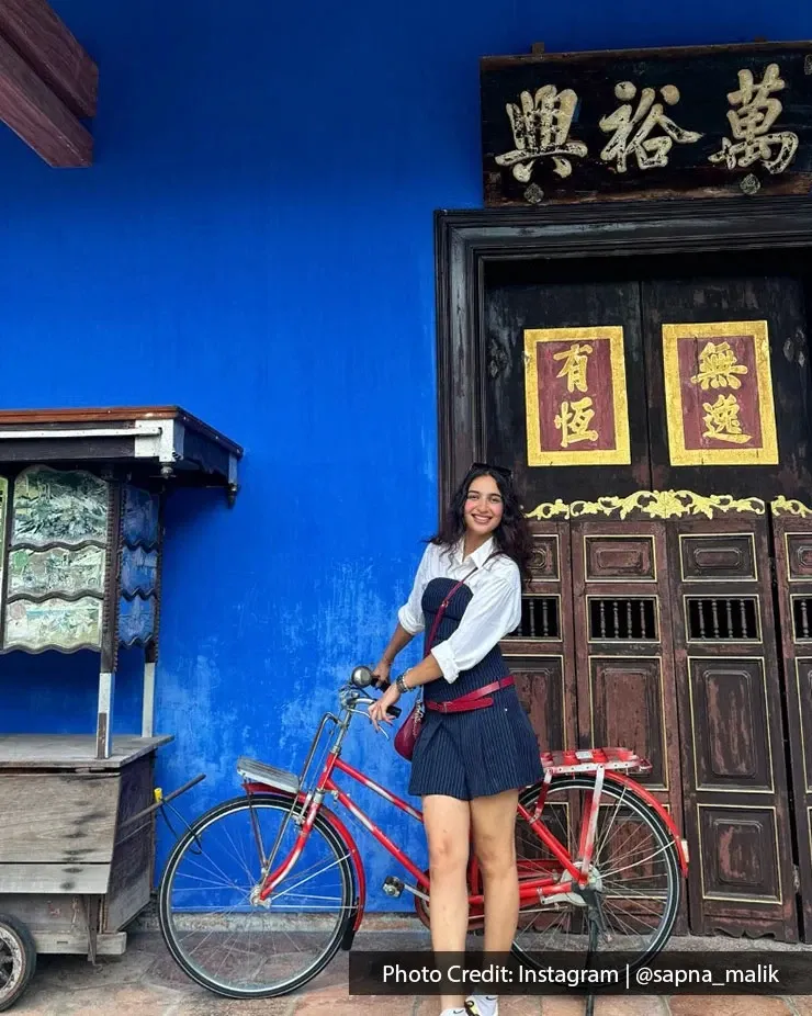 Visitor posing with a bicycle at The Blue Mansion in Penang.