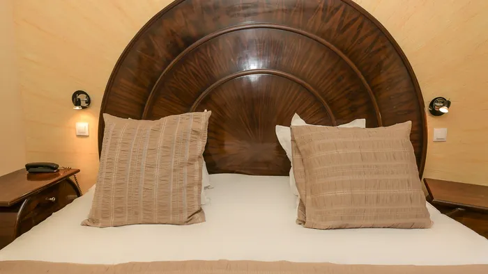 Lit avec tête de lit en bois et oreillers décoratifs à l'Hôtel Villa Aultia.