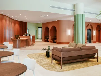 Modern hotel lobby with wood and terracotta decor, couches, tables, and a reception desk at Caulfield Place.