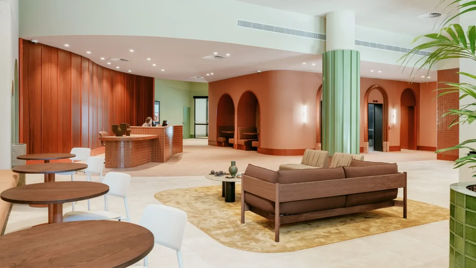 Modern hotel lobby with wood and terracotta decor, couches, tables, and a reception desk at Caulfield Place.
