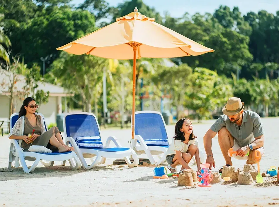 A father and daughter have fun building a sandcastle on a sunny beach - Lexis MY 