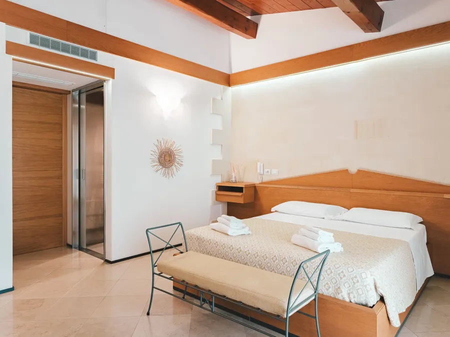 Chambre familiale élégante avec un lit, une banquette et des meubles en bois au Masseria Stali à Caprarica di Lecce.