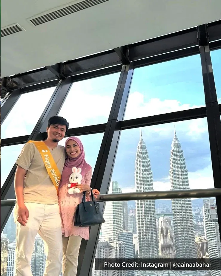 A couple poses happily in front of the Petronas Twin Towers, showcasing the famous skyline of Kuala Lumpur.