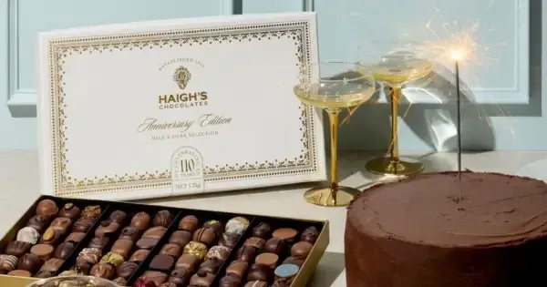 box of chocolates next to two glasses of bubbly and round chocolate cake