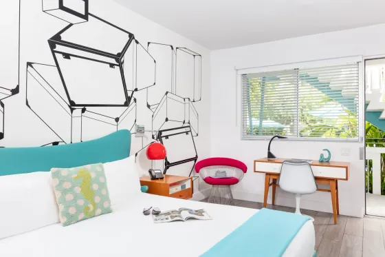 Mid-century modern guest room with king sized bed, vintage red lamp, and a view of the pool stairs