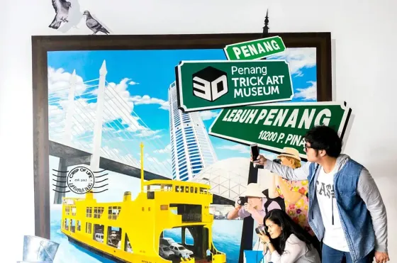 A couple pose together in front of a large painting at the Penang 3D Museum - Lexis Suites Penang