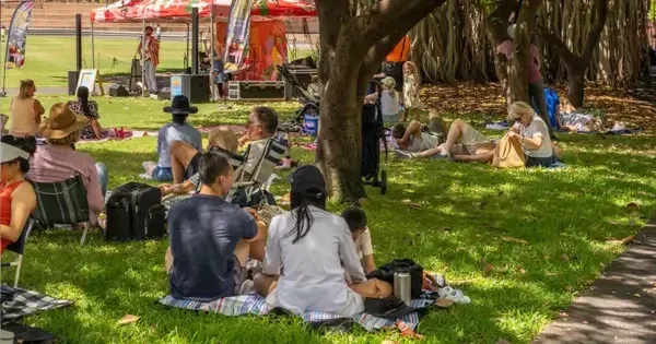 Family sits on grass for picnic enjoying live show