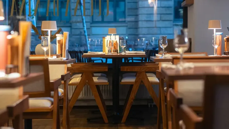 Cozy Cucina da Nina with wooden tables, soft lighting, table lamps, and wine glasses at Flemings Hotel München-City