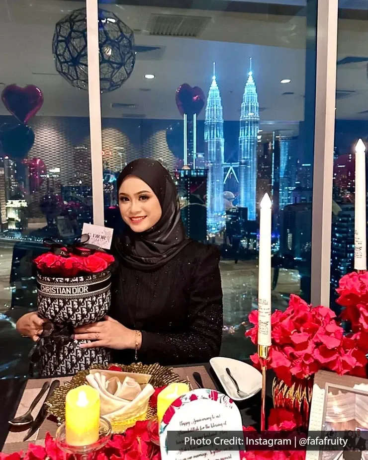 A woman posing for a photo while holding a bouquet of roses in front of the KLCC skyline at night.