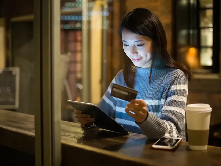 A woman holding her credit card while making an online purchase - Imperial Lexis Kuala Lumpur