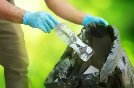 A person throwing a plastic bottle into the trash bag - Grand Lexis Port Dickson