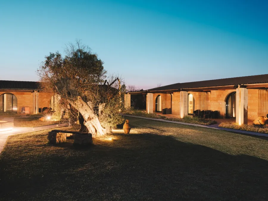 Cour extérieure éclairée de la Masseria Stali avec banc et arbre ancien