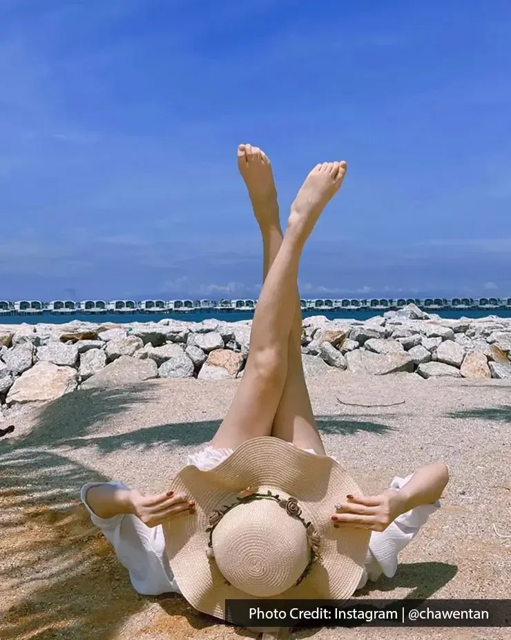 A woman lying down on the beach, posing for a picture with a sea-view background - Lexis MY