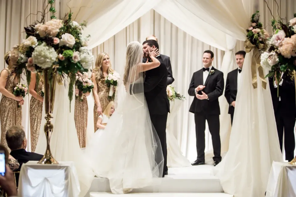 Bride and groom kiss at the altar during a wedding ceremony at the Hotel Arista in Naperville, Illinois.