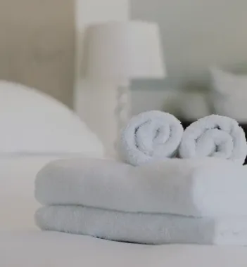 Freshly stacked and rolled white towels on the bed at The Whitehall Houston