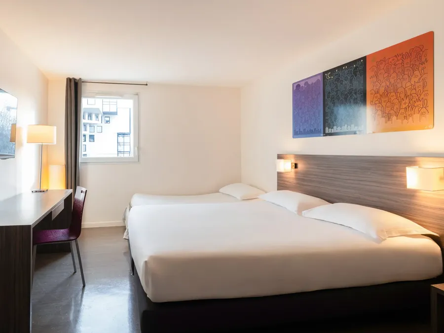 Triple Studio room with a desk and two beds at Appart’Hôtel Hévéa in Valence.