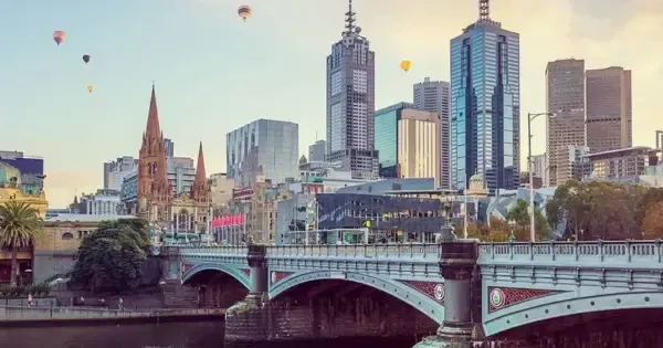 View of Melbourne city skyline at sunrise with hot air balloons floating over the Yarra River and Princes Bridge