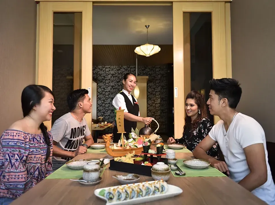 A group of people enjoying their meal while a waitress serving them at a luxury dining venue - Lexis MY 