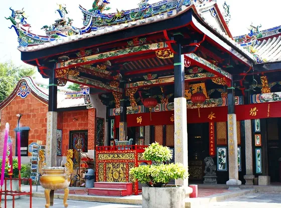 The Snake Temple in Penang, marked by its large red roof, stands out against a clear blue sky - Lexis Suites Penang