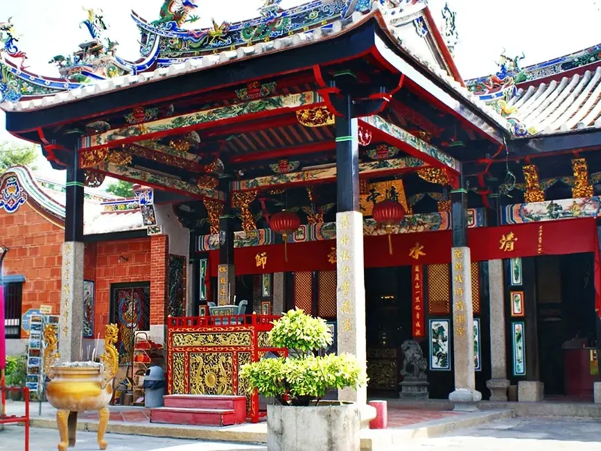 The Snake Temple in Penang, marked by its large red roof, stands out against a clear blue sky - Lexis Suites Penang