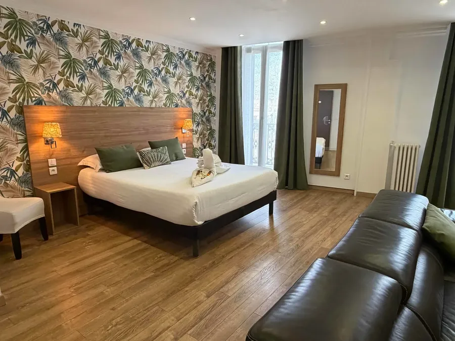 Junior Suite with bed, couch, and wooden floors at Le Grand Hôtel Molière in Pézenas.
