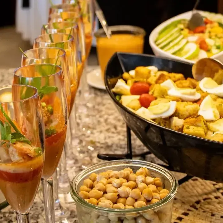 Buffet riche en fruits de mer, légumes, et boissons diverses sur une table élégante.