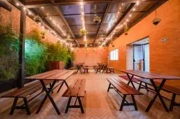 Mesas de picnic de madera en patio de espiga con luces colgantes bajo un techo de cristal en Hotel B3 Virrey
