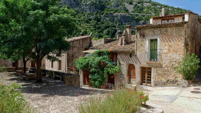 Vue pittoresque de Saint-Guilhem-le-Désert avec des maisons en pierre et une nature luxuriante, à découvrir depuis Le Grand Hôtel Molière à Pézenas.