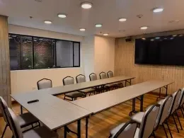 Conference room with wooden tables arranged in a large U shape facing a wall-mounted screen at Unika Hotels