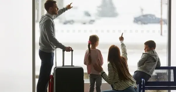 A Family with luggage points out the window of an airport