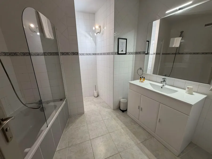 Salle de bain moderne avec douche et baignoire au Grand Hôtel Molière à Pézenas.